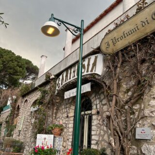 Palo vintage con braccio decorativo e lanterna Capri L300 accesa in Via Matteotti, Capri